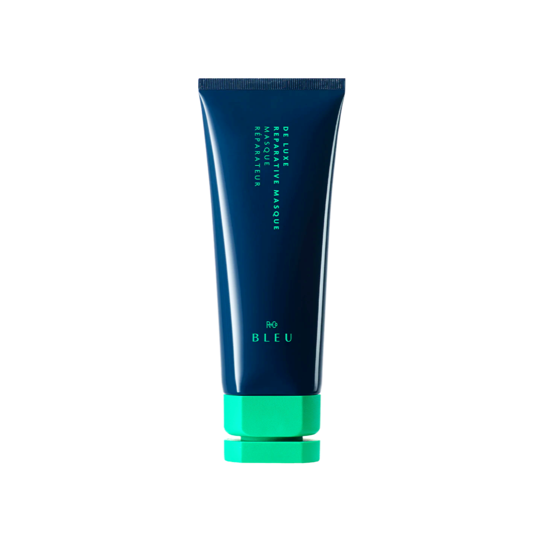 Tube of R+Co BLEU De Luxe Reparative Masque, a restorative hair treatment for dry and damaged hair, in sleek navy blue with a vibrant green cap.