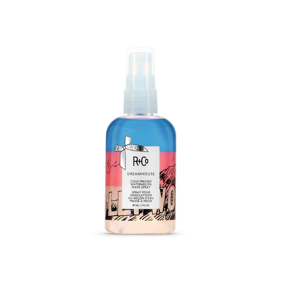 R+Co Dreamhouse Cold Pressed Watermelon Wave Spray, 7.1 fl oz bottle with artistic beach and palm design, for enhancing natural waves and adding shine.