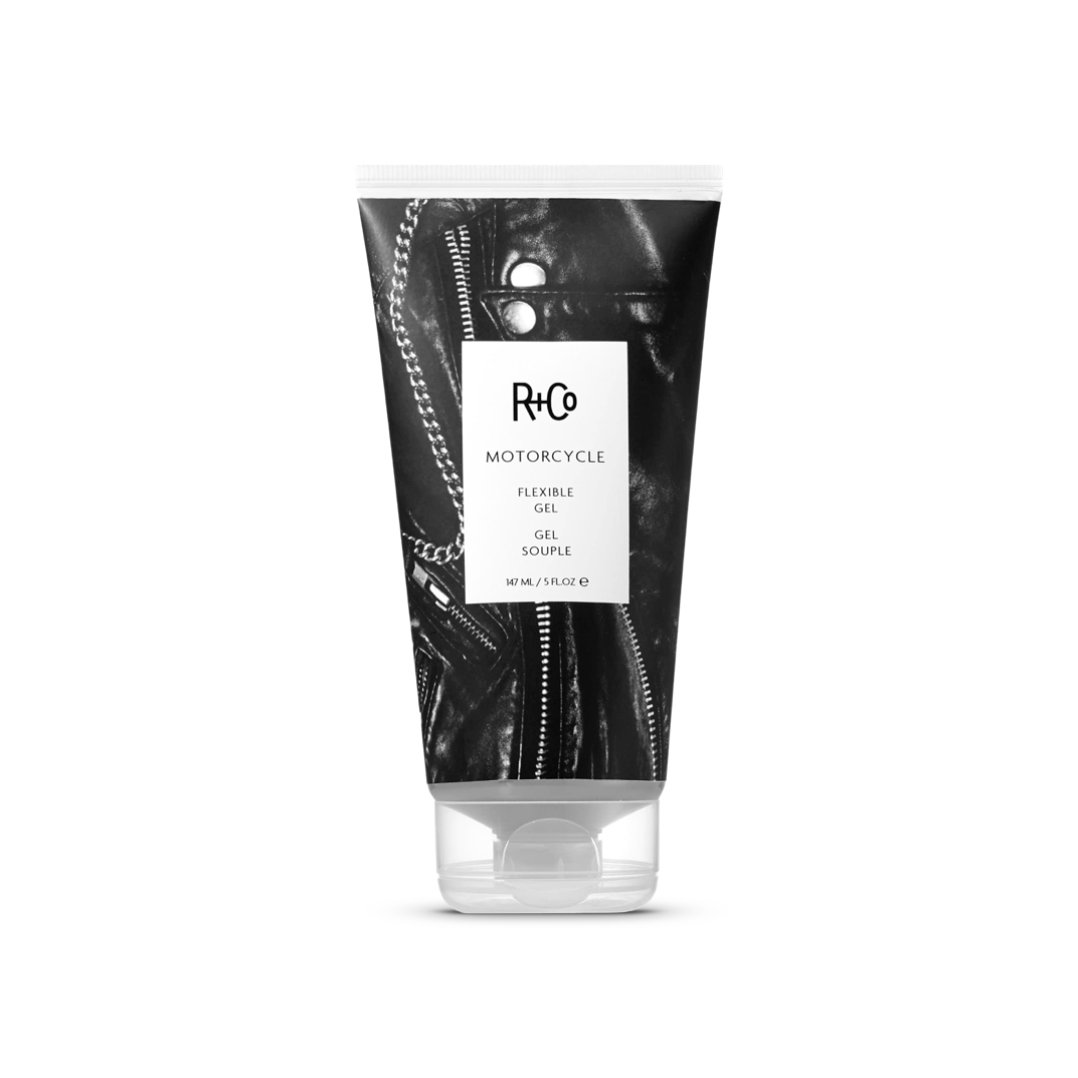 Tube of R+Co MOTORCYCLE Flexible Gel, 147 ml/5 fl oz, against a leather jacket background, conveying the product&#39;s edgy and flexible styling nature.