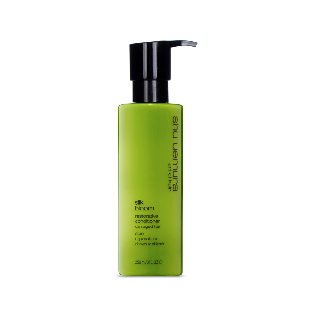 A sleek, lime green bottle of Shu Uemura Silk Bloom Restorative Conditioner with a black pump dispenser. The bottle, containing 250ml/8fl.oz of product, has the name and purpose clearly labeled in white text, emphasizing its special formula for repairing damaged hair.