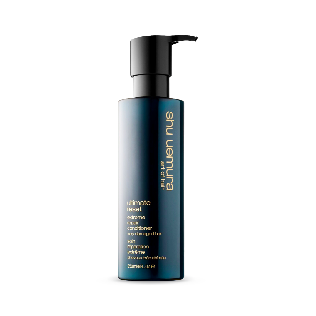 A sophisticated, ombre navy-to-clear bottle of Shu Uemura Ultimate Reset Extreme Repair Conditioner with a practical pump. The 250ml/8fl.oz container promises restorative care for very damaged hair, delivering strength and nourishment with its rice extract formula.