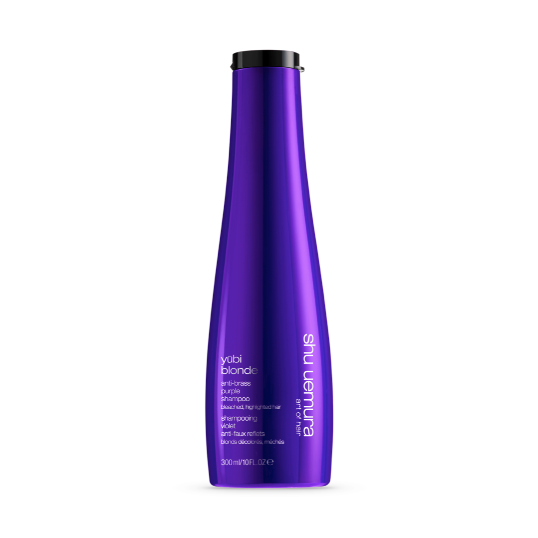 A vibrant purple bottle of Shu Uemura Yūbi Blonde Anti-Brass Purple Shampoo, 300ml, designed to care for bleached and highlighted hair. The bottle&#39;s sleek design is complemented by white and light purple text, outlining the product&#39;s purpose and usage.